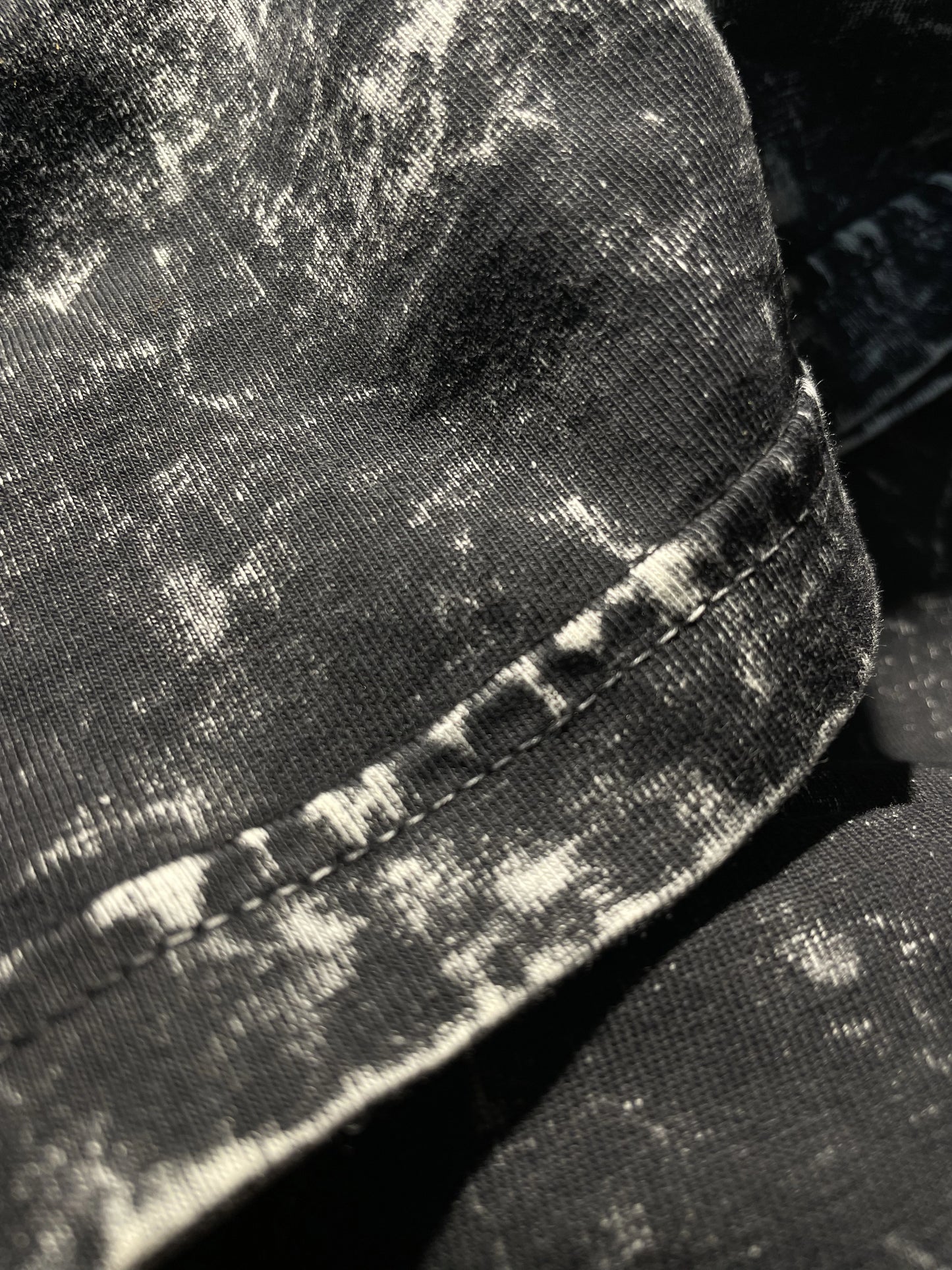 Close-up of the sleeve stitching on East Of Eden’s Deathless tee, highlighting clean, durable construction on heavyweight acid-washed cotton. The distressed black-and-white pattern complements the grunge Indian Christian streetwear aesthetic.