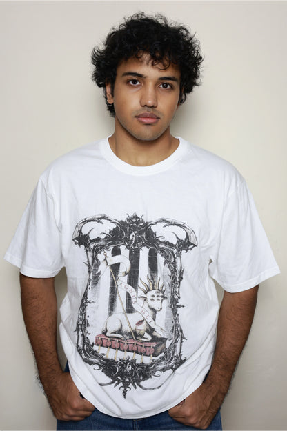 White oversized t-shirt worn by a model, featuring the “Agnus Dei” design: a lamb with seven eyes and horns seated on the Book with Seven Seals, framed by ornate gothic elements — part of your grunge Indian Christian streetwear line.