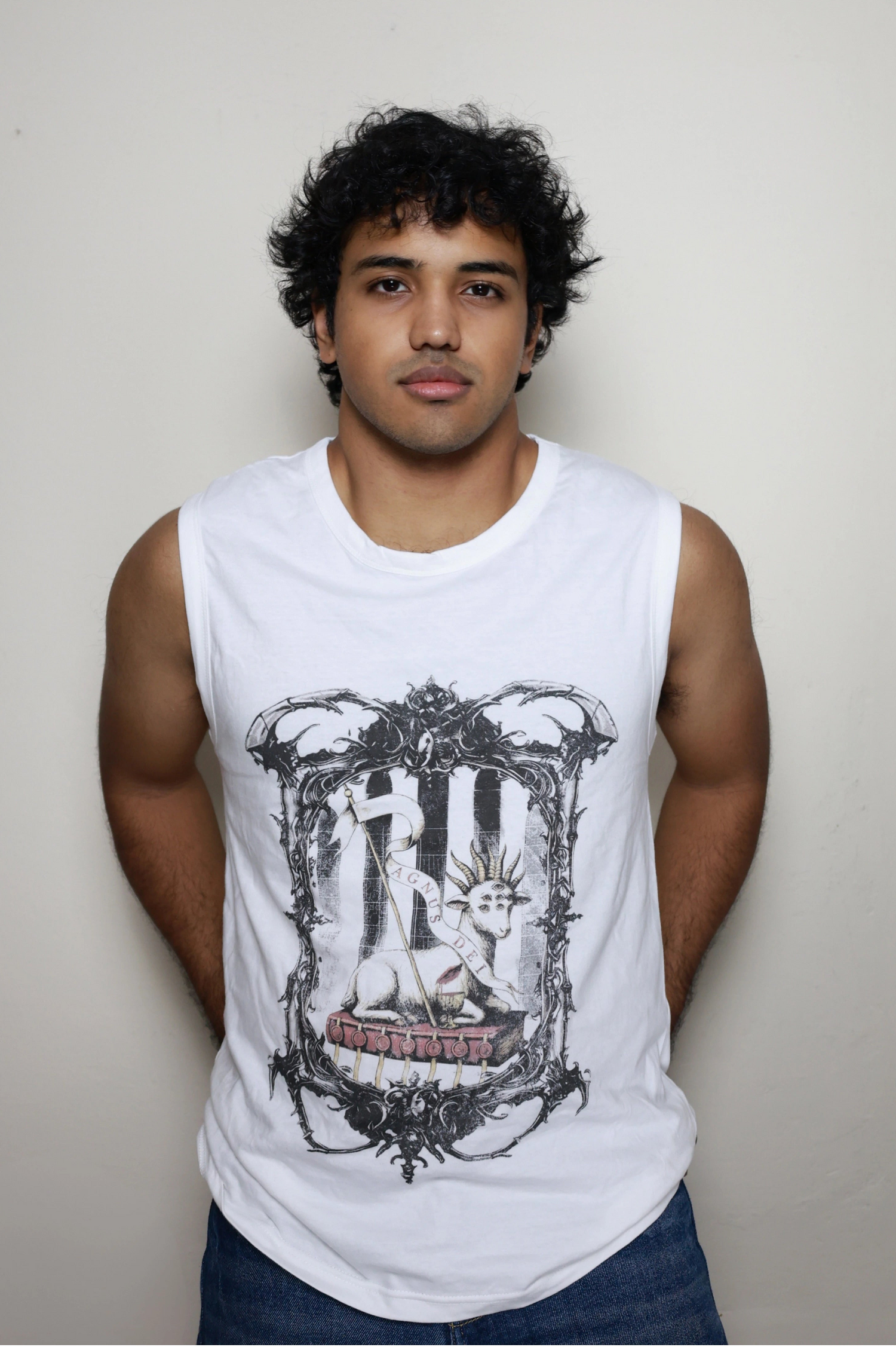 White sleeveless tank top with a bold Agnus Dei design from Revelation: the lamb is shown with seven eyes and horns, resting on the book with seven seals and holding a banner, set within an ornate gothic frame — a key piece in your grunge Indian Christian streetwear line.