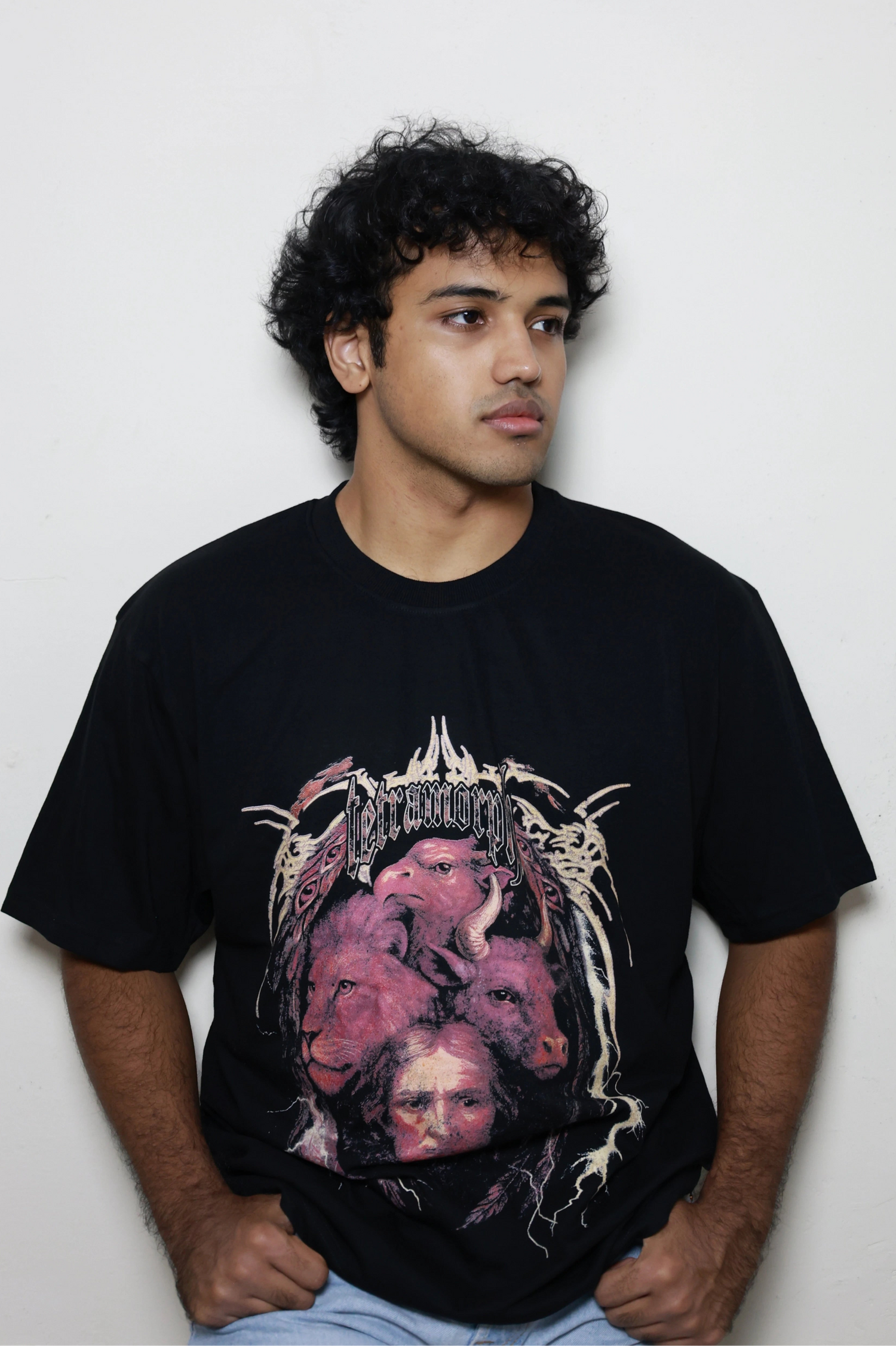 Black oversized t-shirt featuring a bold Tetramorph graphic from Revelation, with the faces of a lion, ox, eagle, and man framed by jagged lightning-like branches. Modeled here as a standalone piece in the grunge Indian Christian streetwear line.