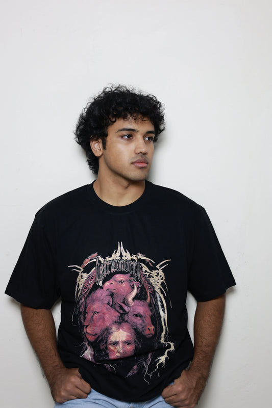Black oversized t-shirt featuring a bold Tetramorph graphic from Revelation, with the faces of a lion, ox, eagle, and man framed by jagged lightning-like branches. Modeled here as a standalone piece in the grunge Indian Christian streetwear line.