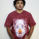 Model wearing a maroon acid-washed t-shirt featuring the “Throne Above Thrones” graphic from Revelation, with a radiant figure seated on a heavenly throne surrounded by lightning and seven flames. A bold piece from the grunge Indian Christian streetwear collection.